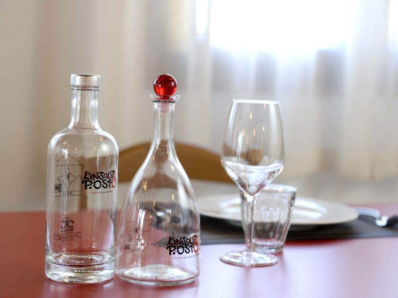 Bottiglie e bicchieri con logo L'Insolito Posto
